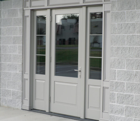 Ultra Series outswing commercial door with sidelites and extruded aluminum raised panels with Sand exterior finish.